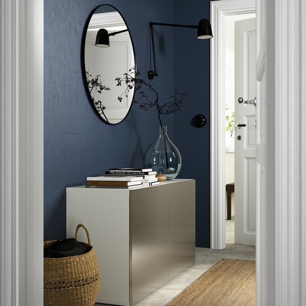 Gold BESTÅ sideboard in navy blue hall, with mirror, books, and plant.