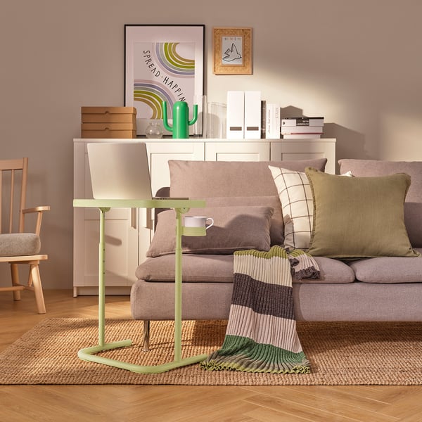 Cosy living room with green laptop stand, grey sofa, and decor.