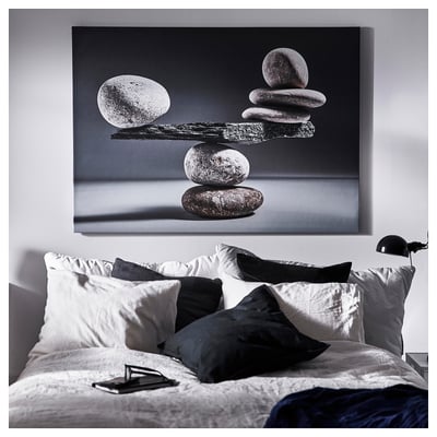 Black & white bedroom with stone art print above bed, table lamp.