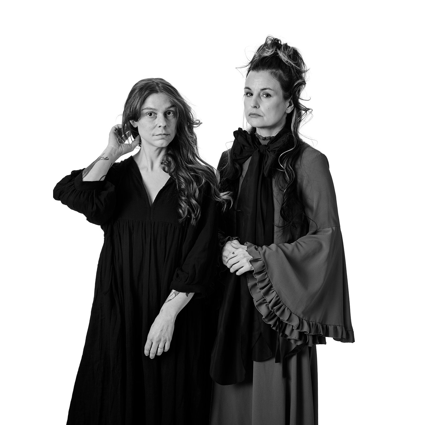 Black and white photo of I Sandström and S Wiking Ekman posing — one in a long black dress, the other in a vintage coat with ruffled accessories.