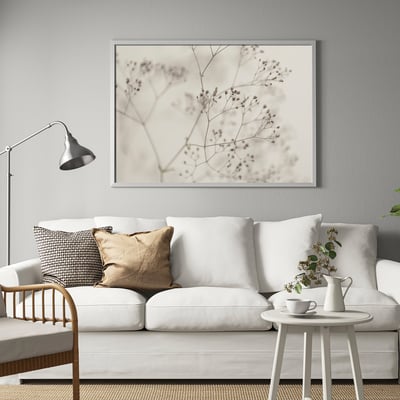 BJÖRKSTA floral art, neutral tones. Modern frame, contrasts with white couch. Contemporary living room.