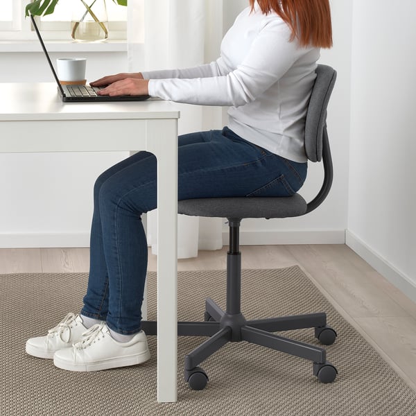 Person sitting at white desk on grey office chair with wheels.