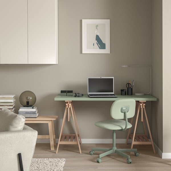 Home office with BLECKBERGET green chair, laptop table, lamp, sofa, and books.
