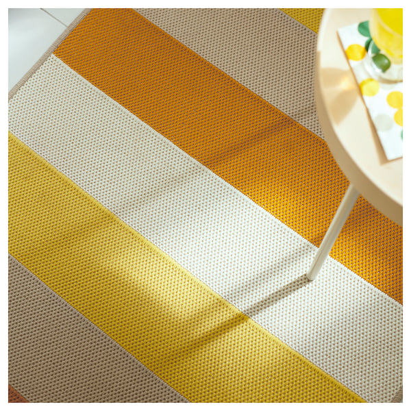 Bright, striped indoor/outdoor rug in yellow and white, laid out on a floor, showcasing its durable and vibrant design.