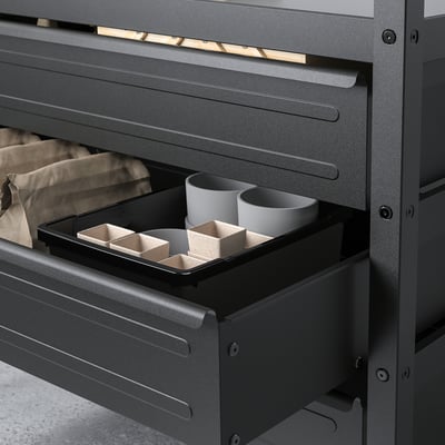 Black metal drawer open showing storage with two mugs and compartments for organising items.