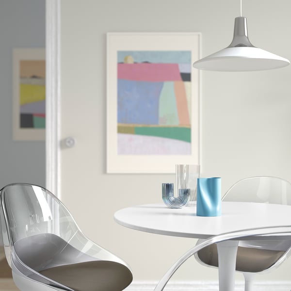 Modern dining area with clear chairs, white table, colourful abstract art, and a blue CHILIFRUKT can on table.