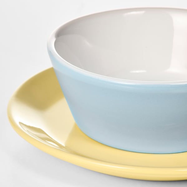 Close-up of a clean, smooth, light blue kids bowl atop a yellow plate.
