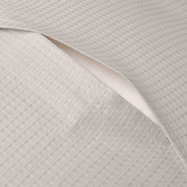 White cushion cover with waffle pattern in cotton. Envelope closing ensures secure fit.