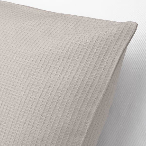 Close-up of a light beige EBBATILDA cushion cover, showcasing its textured waffle pattern on soft cotton.