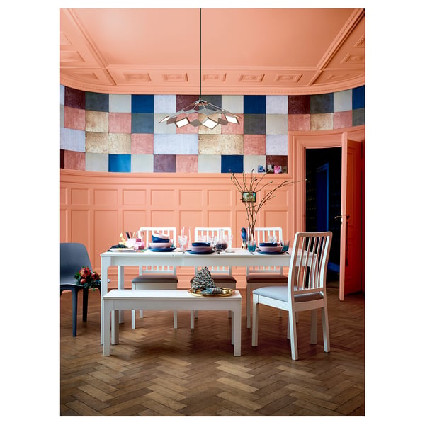 Bright dining room with peach walls, colourful tiled backsplash, white EKEDALEN furniture including a bench, table, and chairs.