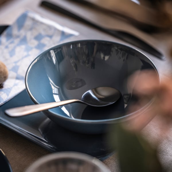 Black ceramic bowl with spoon on table.