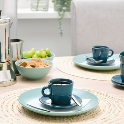 Table setting with blue cups, saucers, and bowls filled with grapes and candies. Coffee is in one cup.