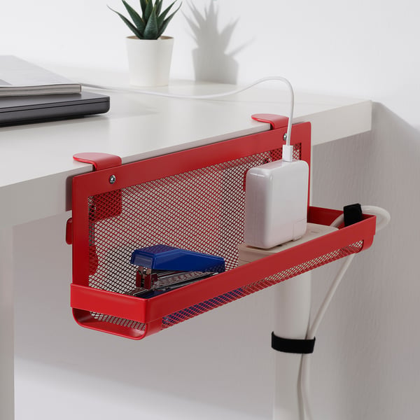 Red desk organiser with a mesh design holds office supplies and a white charger, keeping workspace tidy and organised.