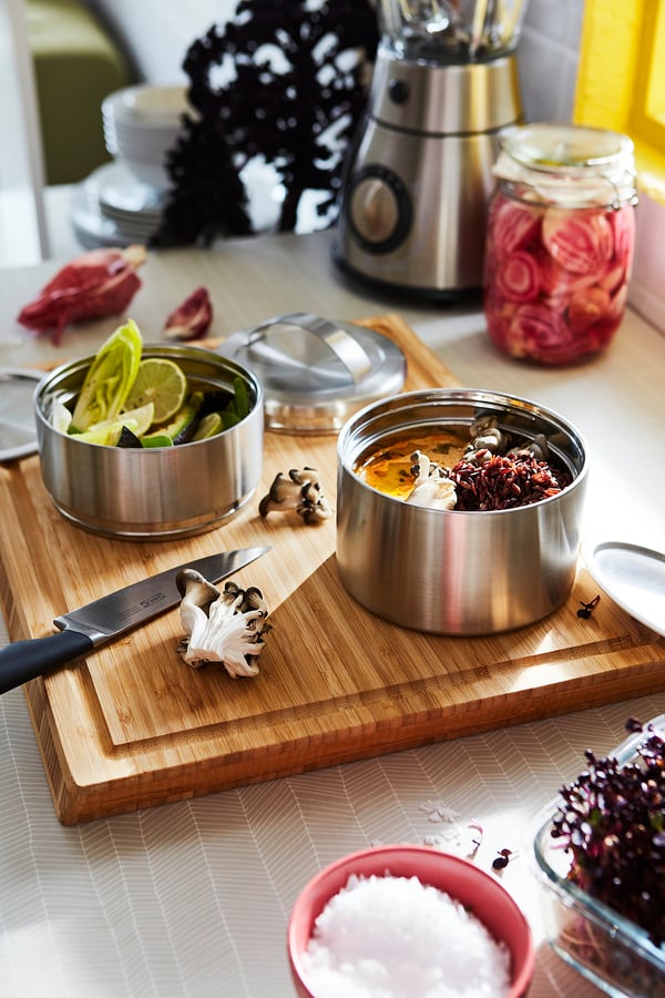 Stainless tiffins, garlic, limes, knife, salt, onions on bamboo.