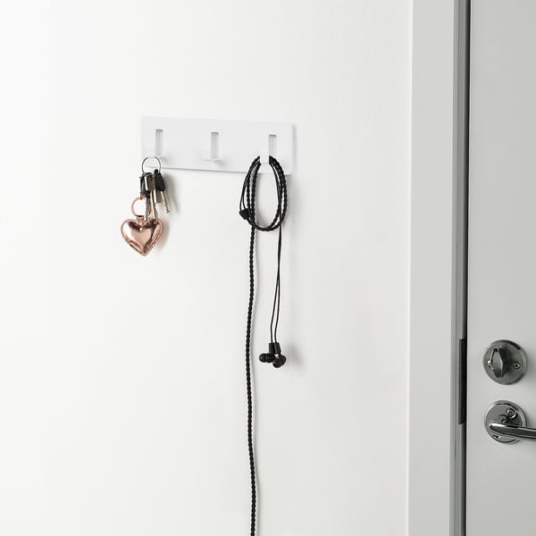 White wall holds keys and earphones with self-adhesive hooks.
