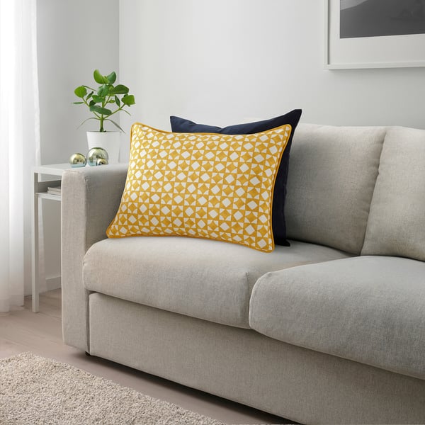 Yellow pillow with white geometric pattern on grey couch, navy complement.