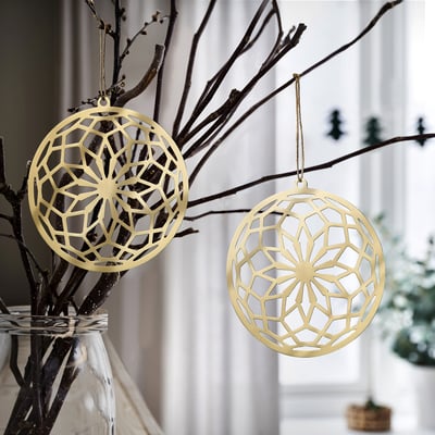 Gold GOKVÄLLÅ ornaments hang on bare branches. Circular, geometric designs. Smaller than decorative vase.