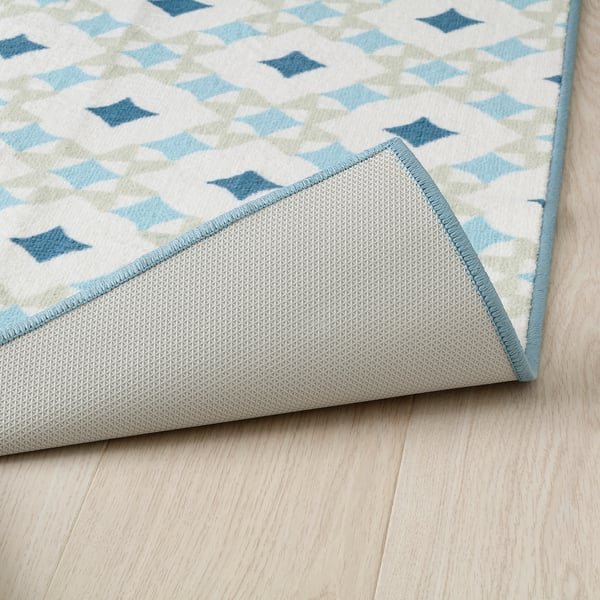 Decorative rug with blue geometric pattern, soft underfoot, laid on wooden floor.