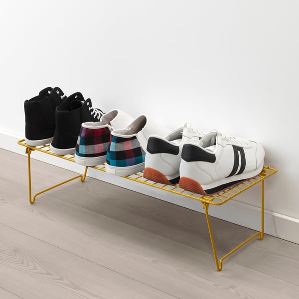 Yellow shoe rack holds 3 pairs of stylish trainers neatly.