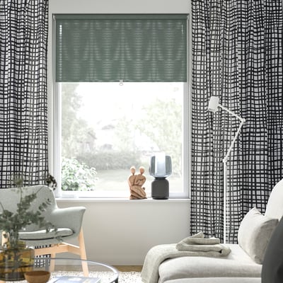 Modern living room with chequered curtains, green blind, wood chair, sofa, and lamp.