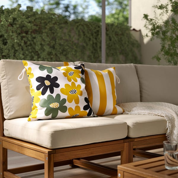 A yellow-green-white floral pillow enhances patio couch comfort.