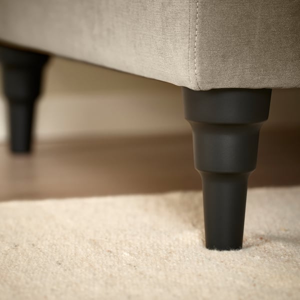Sofa close-up: cardboard back, dark wooden leg, light fabric.