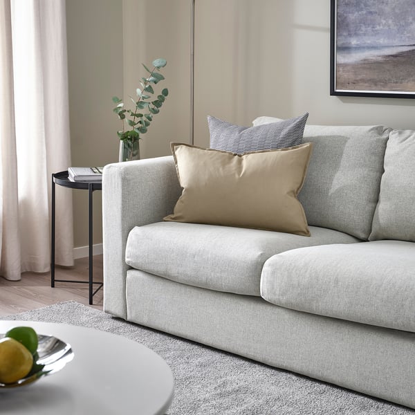 Light grey GURLI cushion on a sofa, 16 x 16, rectangular, with a neutral fabric blend, smaller than the surrounding sofa.