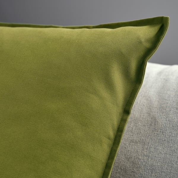 Close-up of a green cushion cover, smooth texture, zip detail, set against plain background.