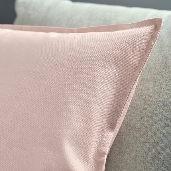 A close-up of a pink cushion cover with a neatly stitched zip, showcasing its smooth texture and clean lines.