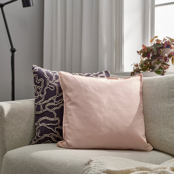 Light pink & dark purple pillows, cosy throw, plant, lamp on couch.