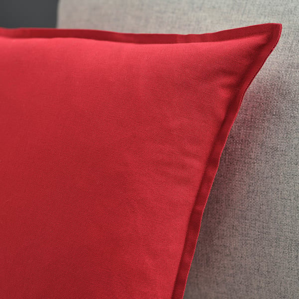Red cushion on a grey couch. Soft, high-quality cotton texture visible.