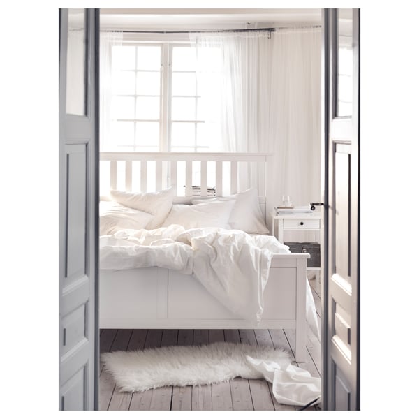 HEMNES white bed, sleek minimalist design, solid wood, plush white bedding, sheer curtains, cosy rug.