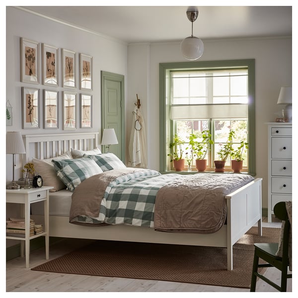 Bright bedroom with white HEMNES bed, green trim window, potted plants, framed art, and green chair.