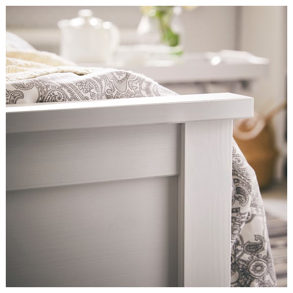 White wooden bed frame, clean and modern, with patterned bedding.