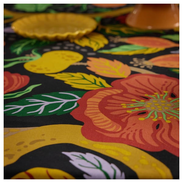 Bright floral tablecloth; vivid reds, yellows on dark background; crisp cotton feel.