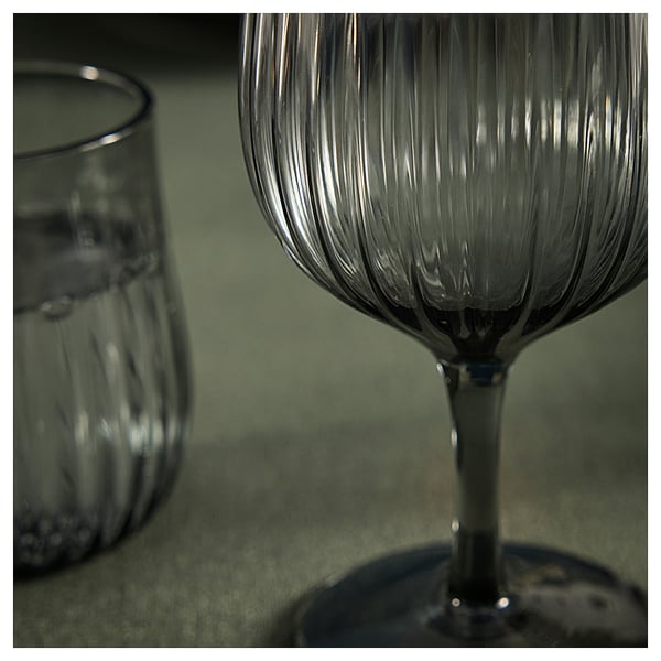 Two textured glasses on green surface; one in focus, one blurred.