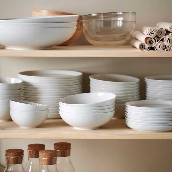 Wooden shelves with white ceramic dishes and bowls, and small glass bottles.