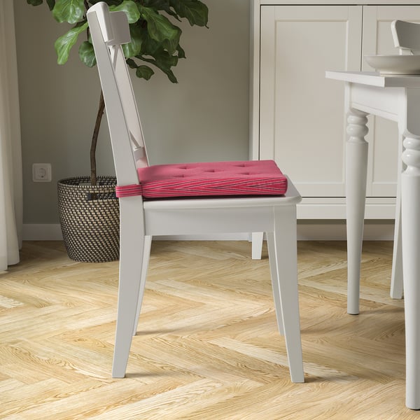 White chair with bright pink cushion, adding comfort and colour.
