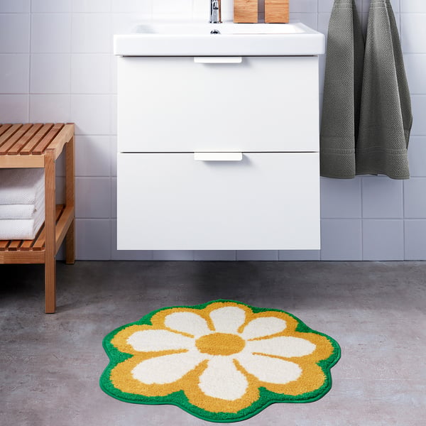 Bathroom with white vanity, grey tiles, colourful KÄRRKNIPPROT mat, and wooden bench with towels.
