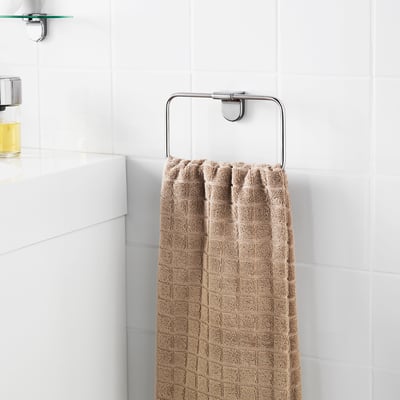 A beige towel hangs on a sleek, chrome bathroom towel holder mounted high on a white tiled wall.