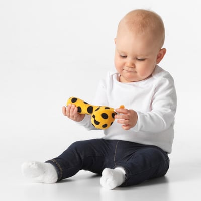 Baby playing with yellow giraffe rattle, sitting, shaking toy.