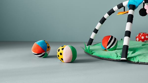 Colourful spherical toys on green mat, striped rods.