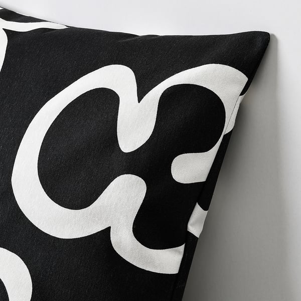 Black and white patterned throw pillow with smooth zip, set against a grey wall.