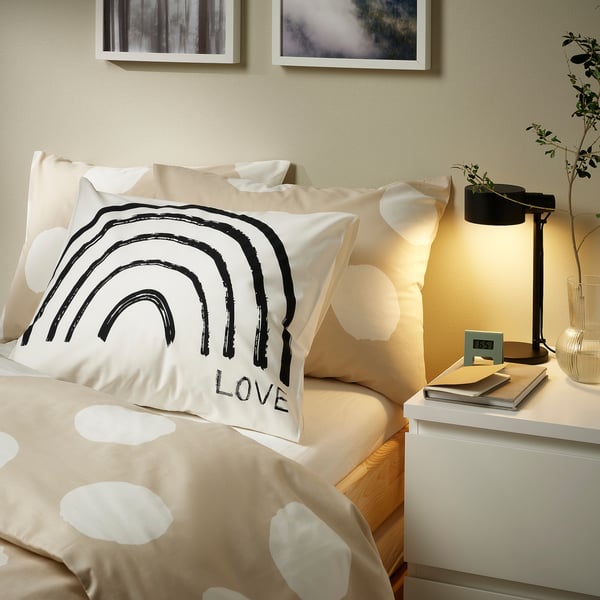 Polka dot duvet set on bed, with small lamp and books.