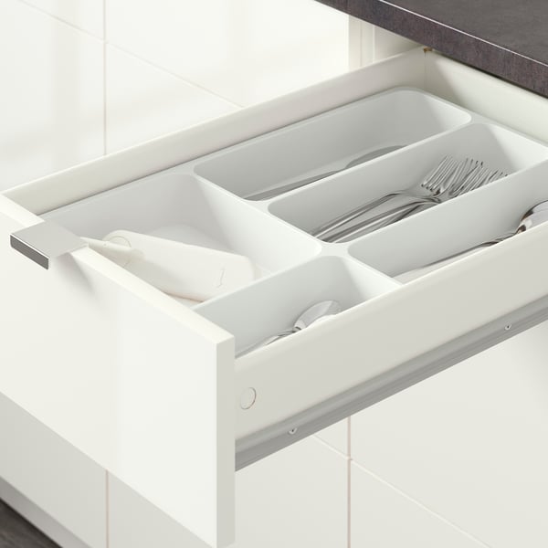 Open kitchen drawer with cutlery organiser: spoons, forks, knives in separate sections.
