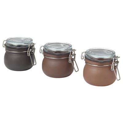 Three KORKEN jars in grey and brown, round shape with glass lids and metal clamps, ideal for storing food.