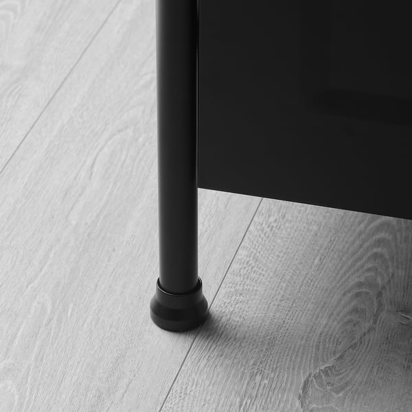 Image shows a close-up of a metal cabinet leg with an adjustable foot on a wooden floor.