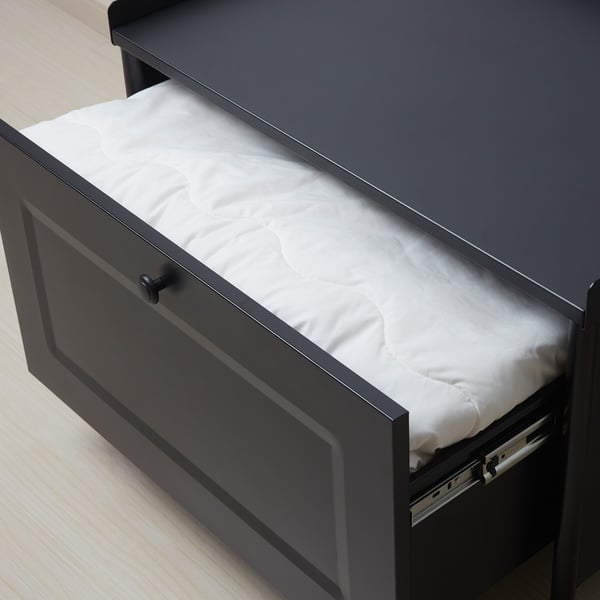 Open drawer filled with folded white sheets on dark wooden unit.