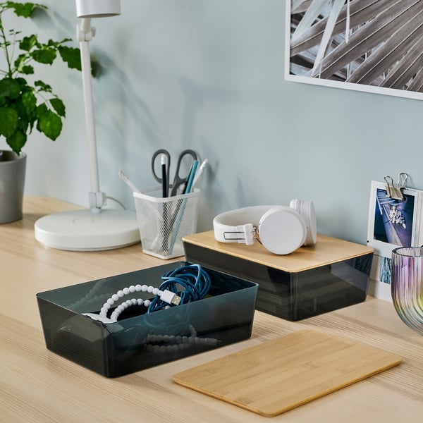 Desk with KUGGIS boxes, plant, headphones, and book support.