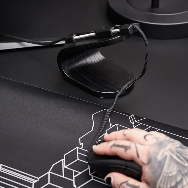 Black mouse bungee with sleek design, keeping cords untangled for gaming. Stainless steel spring, sturdy base, modern aesthetic.